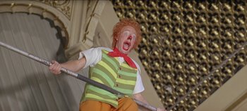 Movie still from “Circus World” (1964), directed by Henry Hathaway – A clown with a red nose is holding a hula hoop; Medium shot, Low angle
