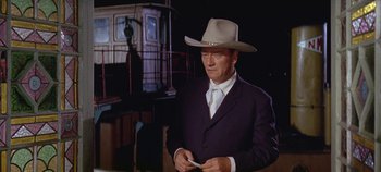 Movie still from “Circus World” (1964), directed by Henry Hathaway – A man in a suit and a cowboy hat holding a cell phone; Medium shot, Low angle