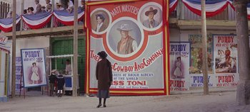 Movie still from “Circus World” (1964), directed by Henry Hathaway – A woman standing in front of a large poster; Wide shot, Low angle