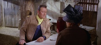 Movie still from “Circus World” (1964), directed by Henry Hathaway – A man sitting at a table in front of a woman; Medium shot, Over the shoulder angle