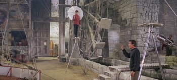 Movie still from “Circus World” (1964), directed by Henry Hathaway – A man holding an umbrella while standing on top of an object; Wide shot, Low angle