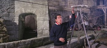 Movie still from “Circus World” (1964), directed by Henry Hathaway – A man standing in front of a building holding a camera; Medium shot, Low angle