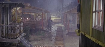Movie still from “Circus World” (1964), directed by Henry Hathaway – A group of people standing on a dock in the rain; Extreme Wide shot, High angle