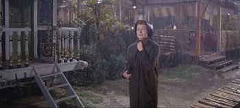 Movie still from “Circus World” (1964), directed by Henry Hathaway – A woman standing in the pouring rain holding a camera; Medium shot, Low angle