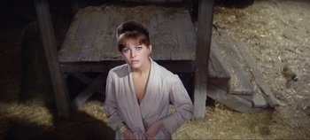 Movie still from “Circus World” (1964), directed by Henry Hathaway – A woman standing in a barn wearing a white robe; Close Up shot, High angle