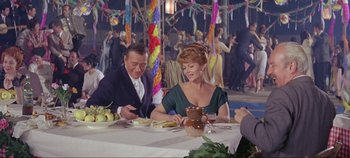 Movie still from “Circus World” (1964), directed by Henry Hathaway – A man and a woman sitting at a dinner table; Medium shot, Over the shoulder angle
