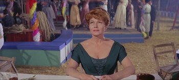 Movie still from “Circus World” (1964), directed by Henry Hathaway – A woman in a green dress sitting in front of a crowd; Medium shot, Low angle