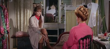 Movie still from “Circus World” (1964), directed by Henry Hathaway – A woman in a pink dress sitting next to another woman in a pink dress; Medium shot, Over the shoulder angle