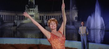 Movie still from “Circus World” (1964), directed by Henry Hathaway – A woman in an orange dress holding a stick; Medium shot, Low angle