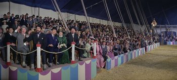 Movie still from “Circus World” (1964), directed by Henry Hathaway – A group of people sitting on top of a stage; Wide shot, High angle