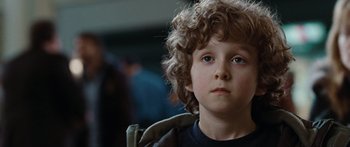 Movie still from “The Day the Earth Stood Still” (2008), directed by Scott Derrickson – A young boy with curly brown hair and blue eyes looking at the camera; Close Up shot, Over the shoulder angle