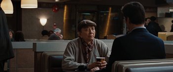 Movie still from “The Day the Earth Stood Still” (2008), directed by Scott Derrickson – An older man sitting at a table holding a cup; Medium shot, Over the shoulder angle
