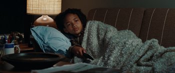 Movie still from “The Day the Earth Stood Still” (2008), directed by Scott Derrickson – A young boy laying on a bed with a remote control; Close Up shot, Over the shoulder angle