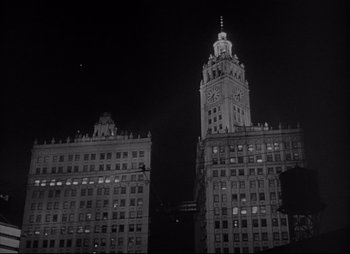 Movie still from “City That Never Sleeps” (1953), directed by John H. Auer – A black - and - white photo of a tall building at night; Extreme Wide shot, Low angle