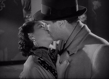 Movie still from “City That Never Sleeps” (1953), directed by John H. Auer – A man and a woman kissing each other in front of a building; Close Up shot, Low angle