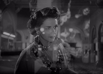 Movie still from “City That Never Sleeps” (1953), directed by John H. Auer – A black - and - white photo of a woman in a room; Close Up shot, Over the shoulder angle