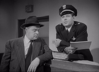 Movie still from “City That Never Sleeps” (1953), directed by John H. Auer – A man in a suit and a man in a police uniform; Medium shot, Low angle