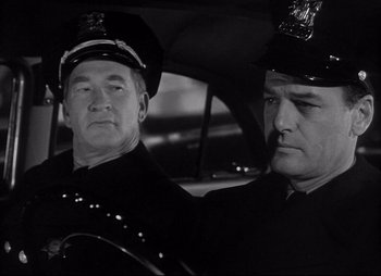 Movie still from “City That Never Sleeps” (1953), directed by John H. Auer – Two police officers sitting in a police car; Close Up shot, Low angle
