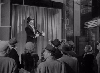 Movie still from “City That Never Sleeps” (1953), directed by John H. Auer – An old photo of a man on a stage speaking to a crowd; Wide shot, Low angle