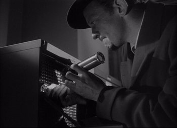 Movie still from “City That Never Sleeps” (1953), directed by John H. Auer – A black and white photo of a man working with an instrument; Close Up shot, Low angle