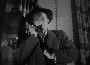 Movie still from “City That Never Sleeps” (1953), directed by John H. Auer – An old photo of a man talking on a phone; Close Up shot, Low angle