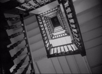 Movie still from “City That Never Sleeps” (1953), directed by John H. Auer – Looking up at a spiral staircase in a building; Wide shot, Overhead angle
