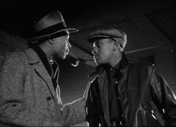 Movie still from “City That Never Sleeps” (1953), directed by John H. Auer – Two men are talking to each other while smoking a pipe; Medium shot, Low angle