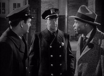 Movie still from “City That Never Sleeps” (1953), directed by John H. Auer – A group of men standing next to each other; Medium shot, Over the shoulder angle