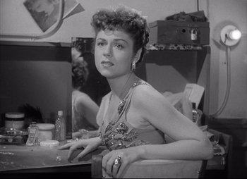 Movie still from “City That Never Sleeps” (1953), directed by John H. Auer – A black and white photo of a woman sitting in front of a mirror; Close Up shot, Low angle