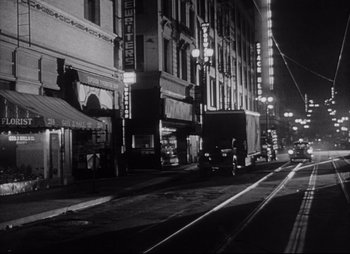 Movie still from “City That Never Sleeps” (1953), directed by John H. Auer – A black - and - white photo of a city street at night; Extreme Wide shot, Low angle