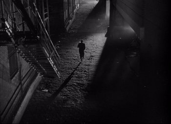Movie still from “City That Never Sleeps” (1953), directed by John H. Auer – A man walking down a street at night; Extreme Wide shot, High angle