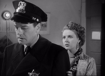 Movie still from “City That Never Sleeps” (1953), directed by John H. Auer – A man and a woman standing next to each other in a room; Close Up shot, Low angle