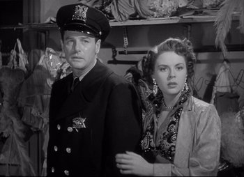 Movie still from “City That Never Sleeps” (1953), directed by John H. Auer – A man and a woman standing next to each other; Medium shot, Low angle