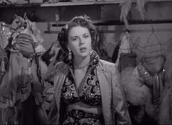 Movie still from “City That Never Sleeps” (1953), directed by John H. Auer – A black and white photo of a woman in a dress; Medium shot, Over the shoulder angle