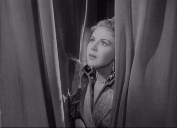 Movie still from “City That Never Sleeps” (1953), directed by John H. Auer – A black - and - white photo of a woman looking out a window; Medium shot, Low angle