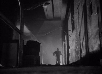 Movie still from “City That Never Sleeps” (1953), directed by John H. Auer – A man is walking in a dark alley way; Wide shot, Low angle