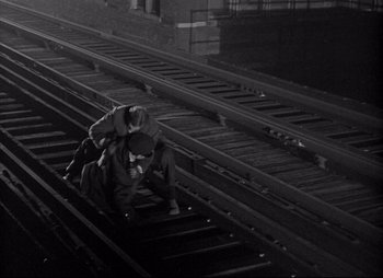 Movie still from “City That Never Sleeps” (1953), directed by John H. Auer – Two people are sitting on a train track; Wide shot, Overhead angle