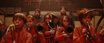 Movie still from “City of Ember” (2008), directed by Gil Kenan – A group of young people in orange jackets holding brass instruments; Medium shot, Low angle