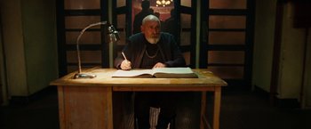 Movie still from “City of Ember” (2008), directed by Gil Kenan – An old man sitting at a table writing on a book; Medium shot, Low angle