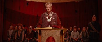 Movie still from “City of Ember” (2008), directed by Gil Kenan – A man wearing a chain around his neck is standing at a lectern; Medium shot, Low angle