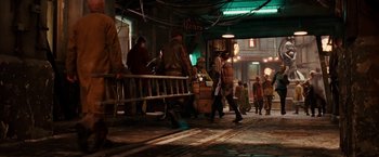 Movie still from “City of Ember” (2008), directed by Gil Kenan – A group of people walking down a street at night; Wide shot, High angle