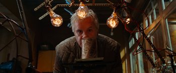 Movie still from “City of Ember” (2008), directed by Gil Kenan – A man is drinking from a paper cup in front of some lights; Close Up shot, Low angle