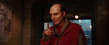 Movie still from “City of Ember” (2008), directed by Gil Kenan – A bald man in a red jacket is holding his finger up; Close Up shot, Low angle