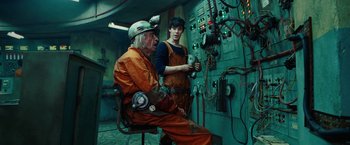 Movie still from “City of Ember” (2008), directed by Gil Kenan – Two men in orange overalls and hard hats working in an electrical room; Medium shot, Over the shoulder angle