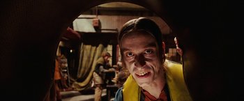 Movie still from “City of Ember” (2008), directed by Gil Kenan – A man in a yellow and blue shirt is smiling for the camera; Close Up shot, Low angle
