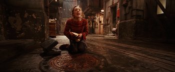 Movie still from “City of Ember” (2008), directed by Gil Kenan – A woman sitting on the ground in the middle of a street; Wide shot, High angle