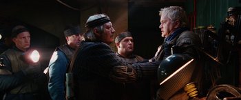 Movie still from “City of Ember” (2008), directed by Gil Kenan – A group of men standing next to each other in a room; Medium shot, Over the shoulder angle