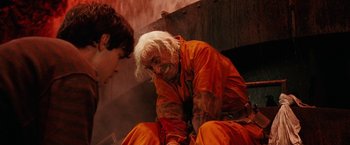Movie still from “City of Ember” (2008), directed by Gil Kenan – An old man in orange is sitting next to a young man; Medium shot, Overhead angle