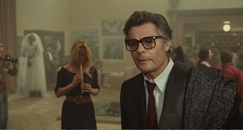 Movie still from “City of Women” (1980), directed by Federico Fellini – A man wearing a suit and glasses in front of a woman; Medium shot, Low angle