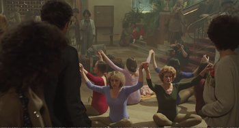 Movie still from “City of Women” (1980), directed by Federico Fellini – A group of women sitting on the ground with their arms in the air; Wide shot, High angle